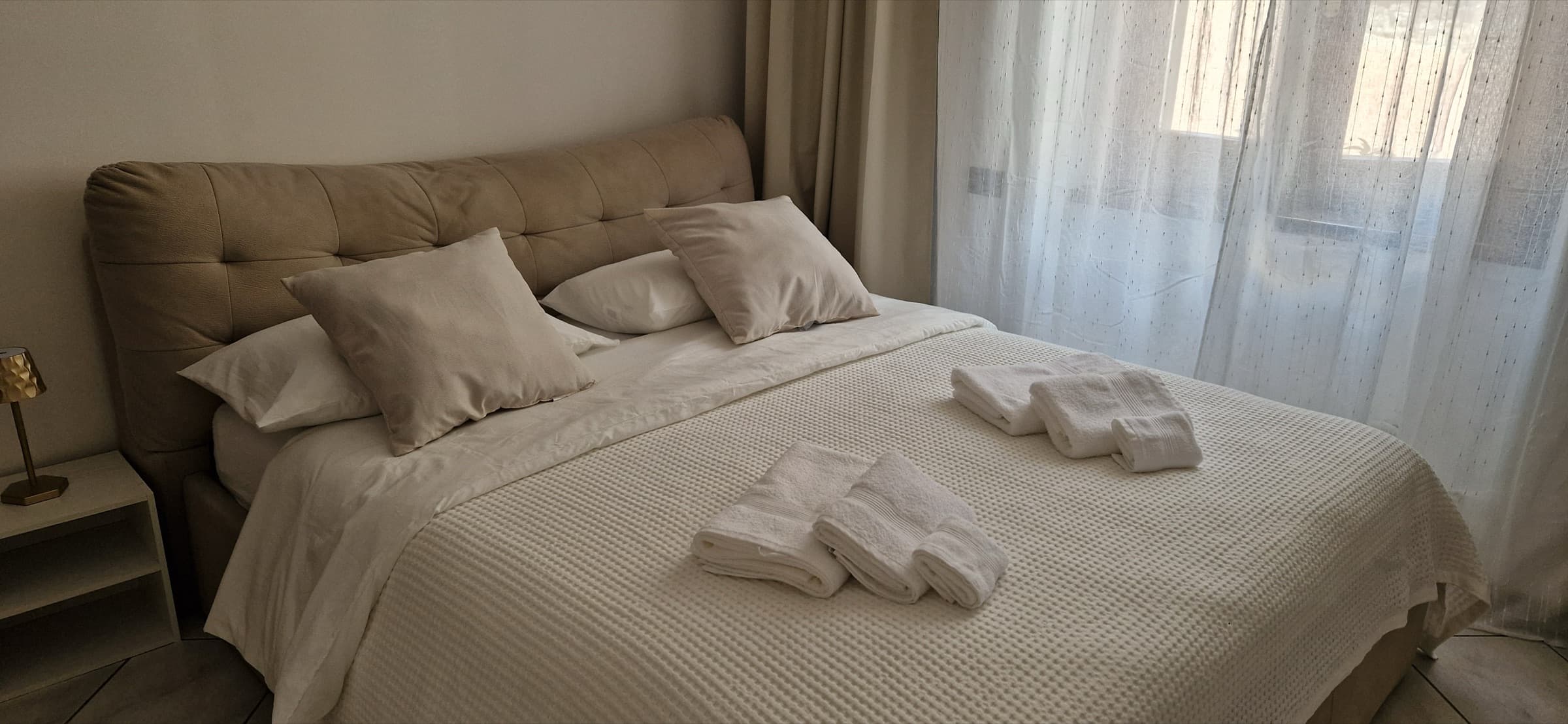 The bedroom at Terra Intelvi: a double bed made up in white linen beside a curtained window
